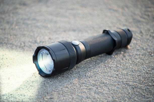 pocket LED flashlight lies on a sand. Lantern for tourism and daily use EDC